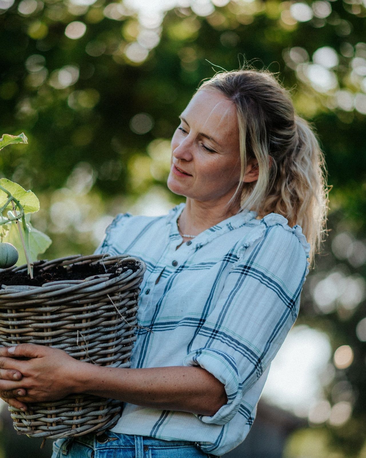 Frau mit Korb und Pflanze im Garten